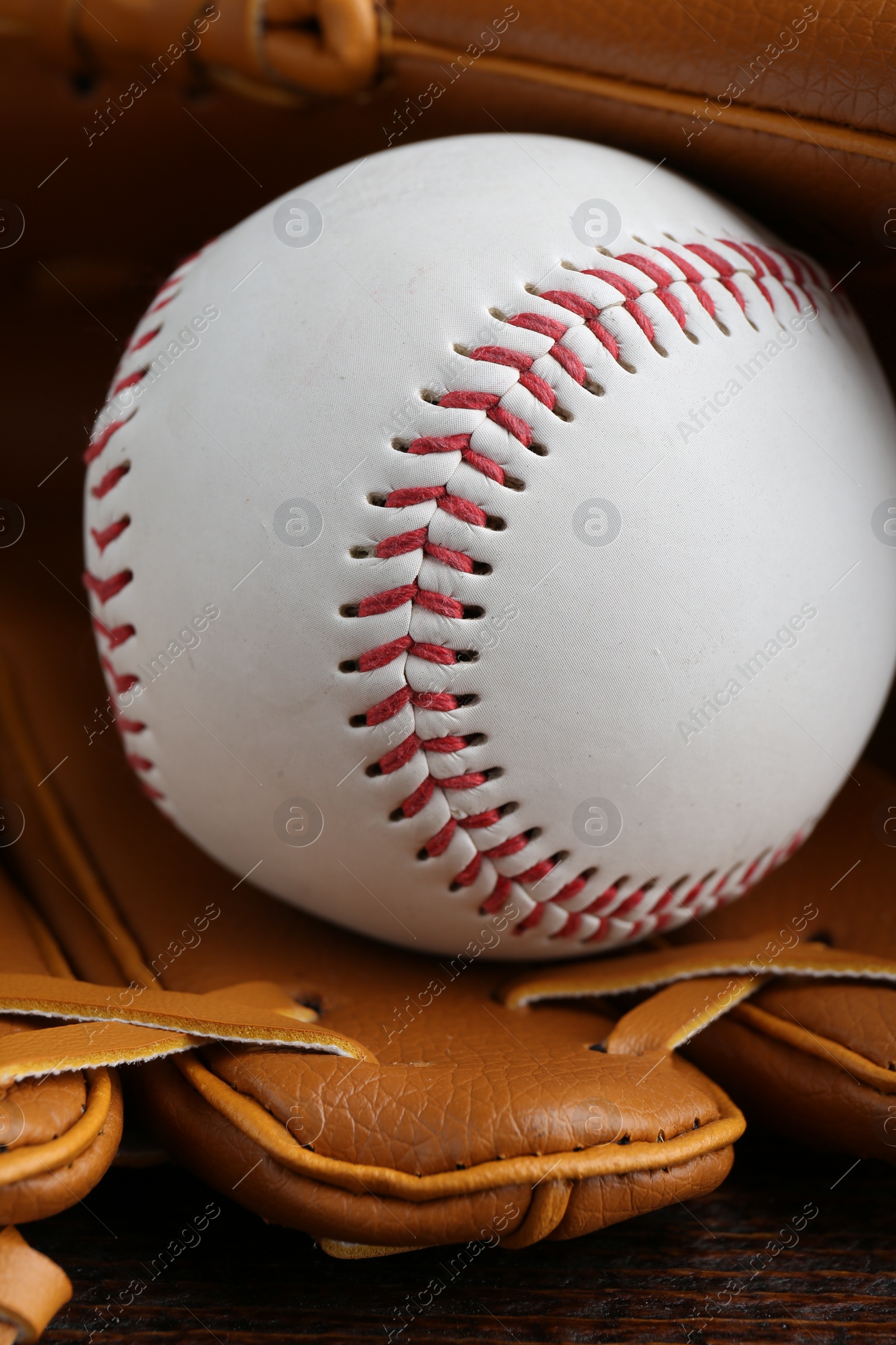 Photo of Leather baseball glove with ball on wooden table, closeup