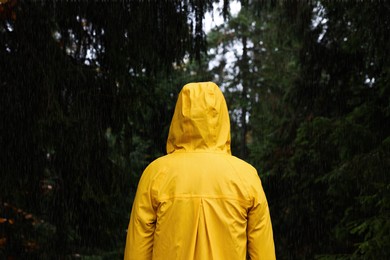 Photo of Woman with raincoat in forest under rain, back view