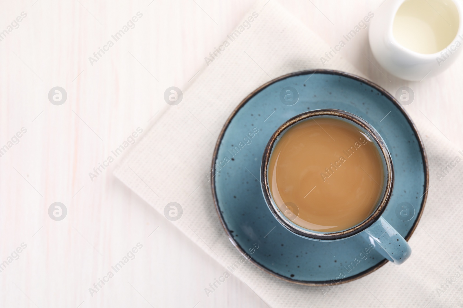 Photo of Delicious coffee in cup and milk on white wooden table, top view. Space for text