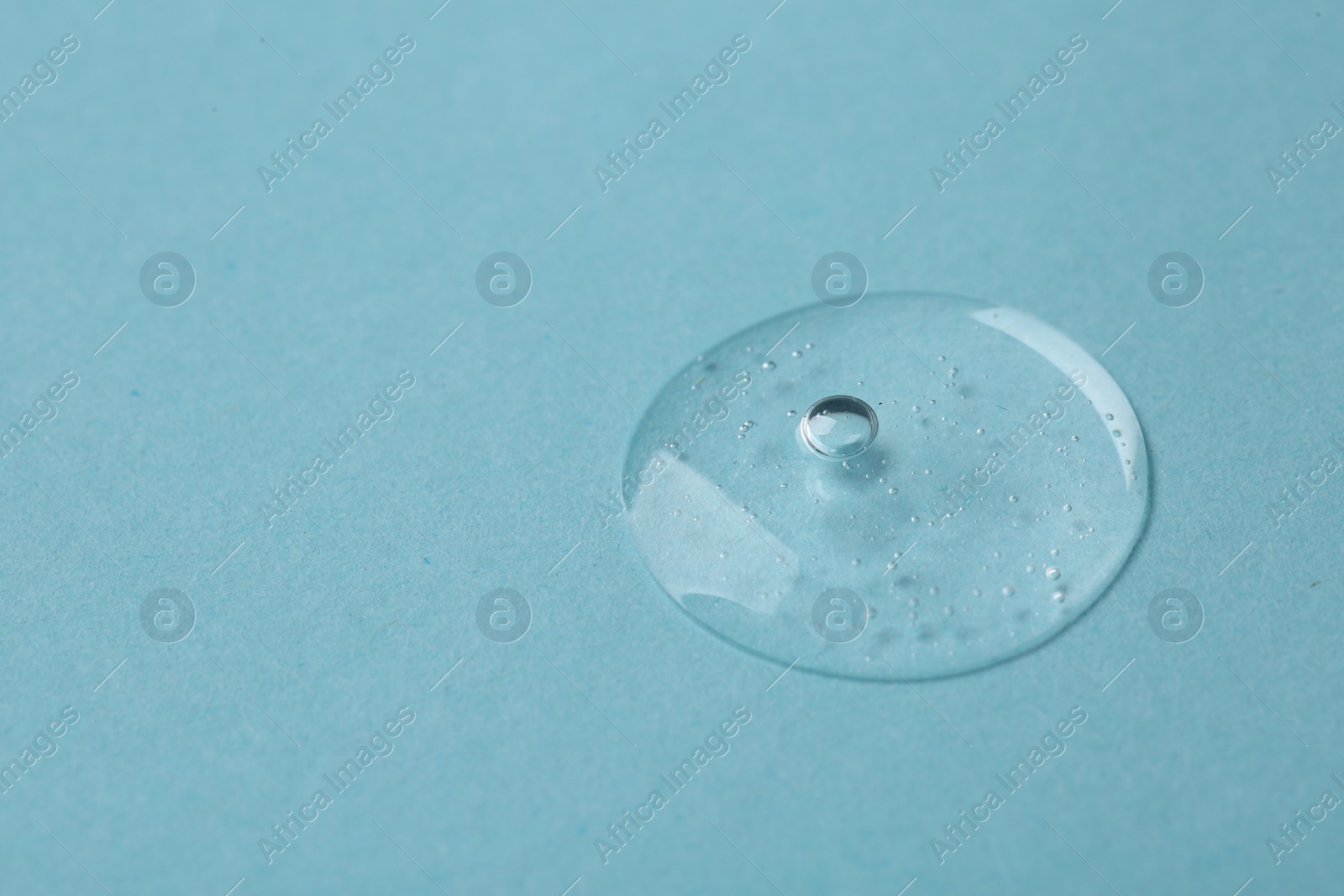 Photo of Sample of cosmetic serum on light blue background, closeup. Space for text