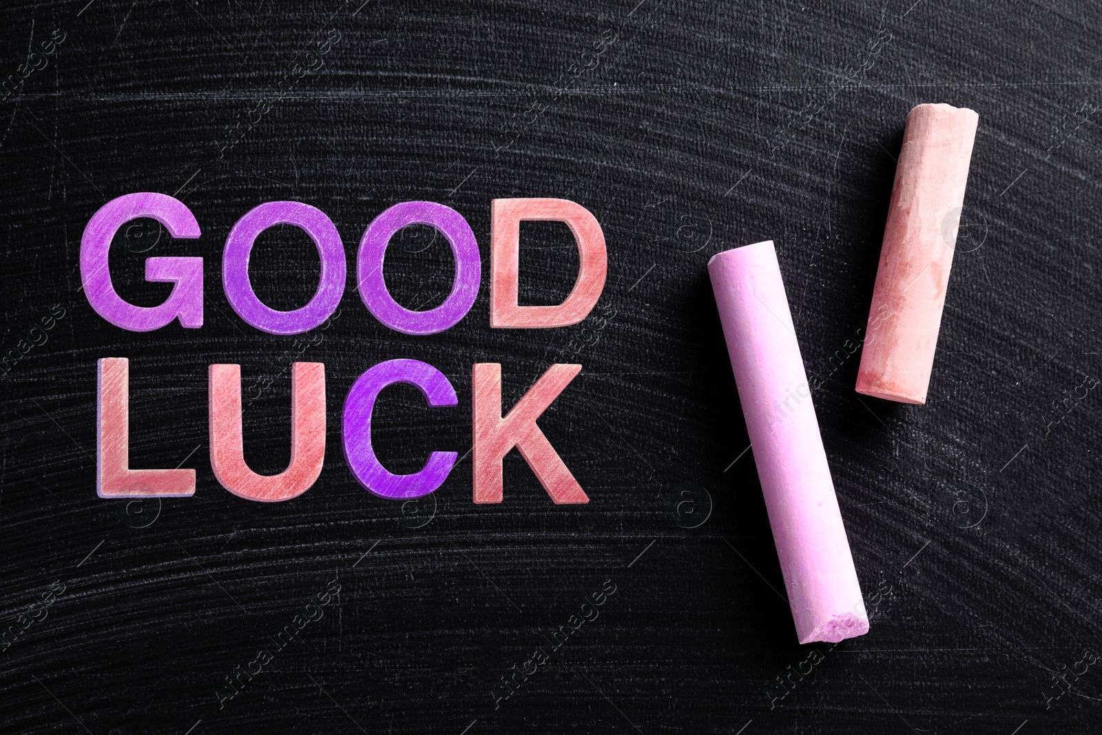 Image of Pieces of color chalk and phrase GOOD LUCK on blackboard, flat lay