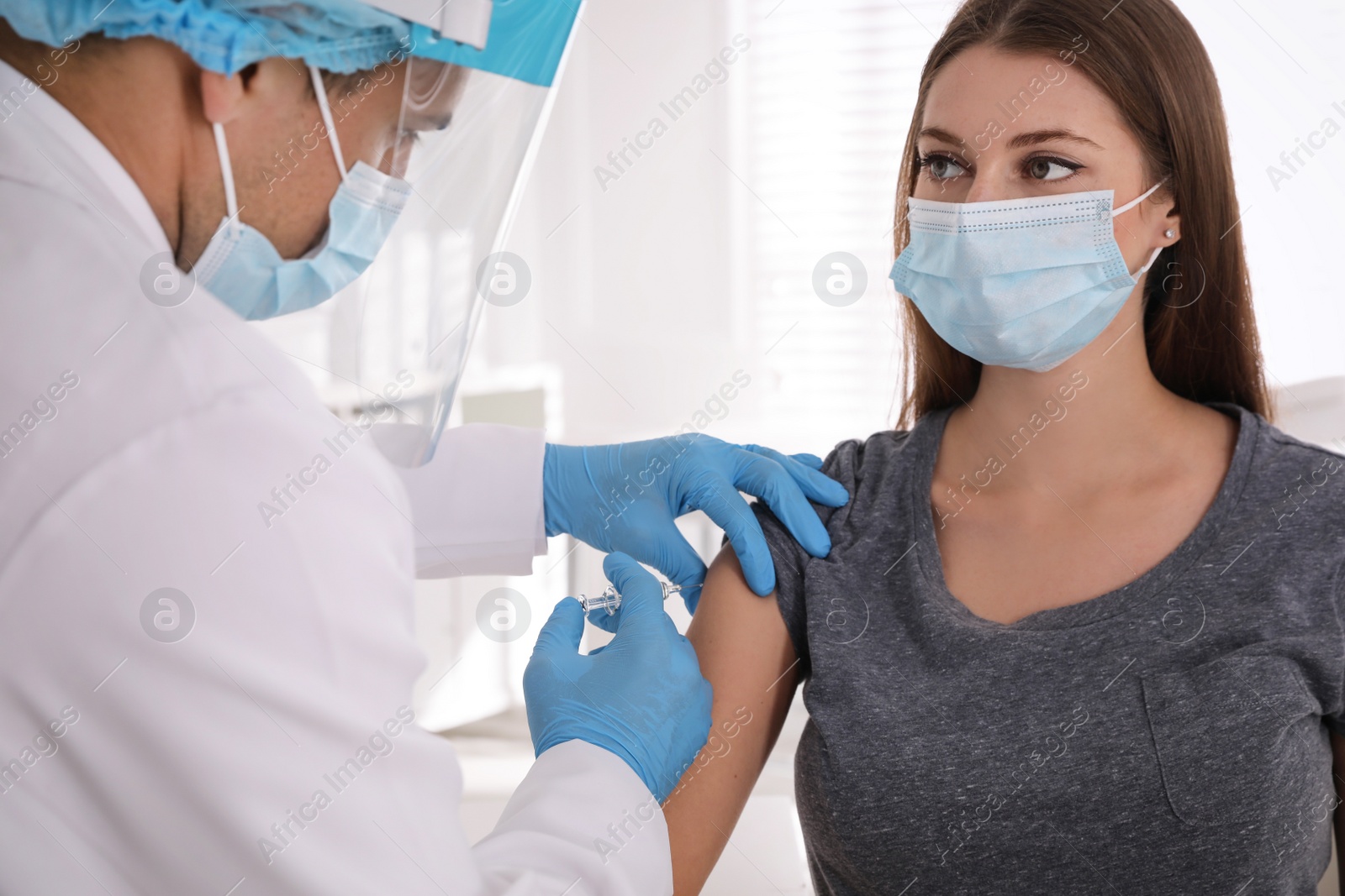 Photo of Doctor vaccinating young woman against Covid-19 in clinic