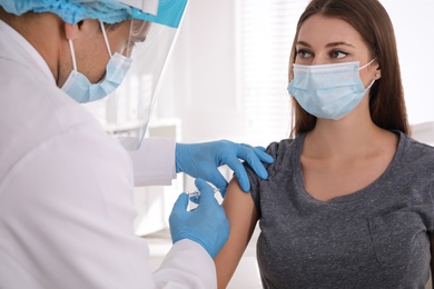 Photo of Doctor vaccinating young woman against Covid-19 in clinic