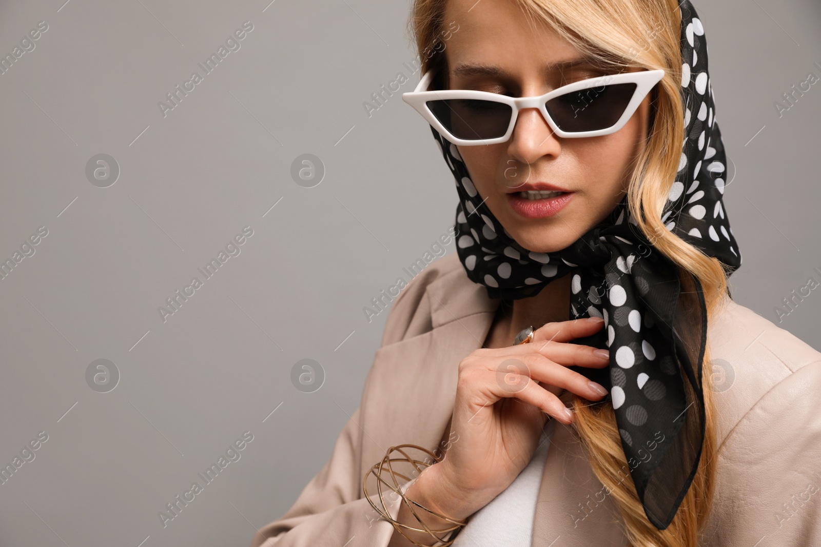 Photo of Young woman with sunglasses and stylish bandana on grey background, closeup. Space for text