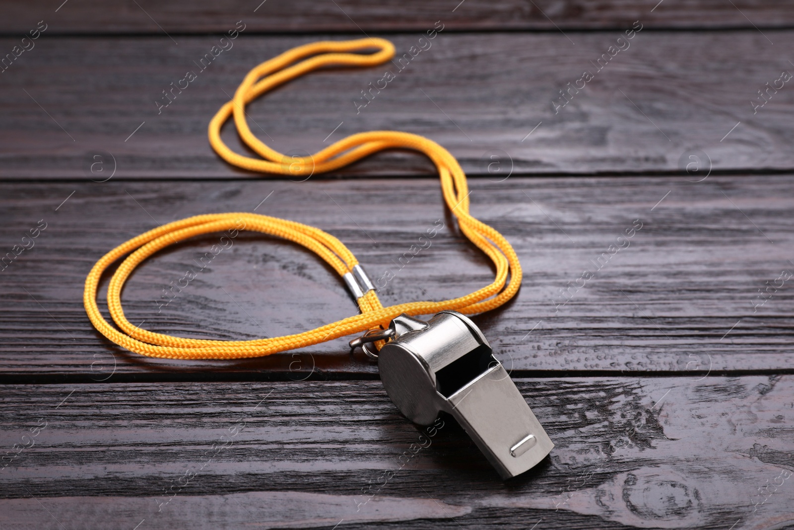 Photo of One metal whistle with cord on wooden table