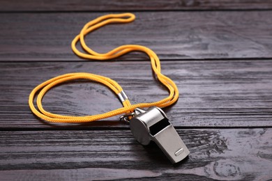 One metal whistle with cord on wooden table