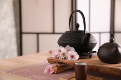 Beautiful traditional tea ceremony set and sakura flowers on wooden table. Space for text