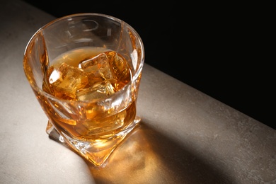 Golden whiskey in glass with ice cubes on table. Space for text