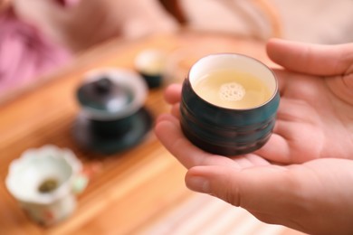 Photo of Guest with cup of freshly brewed tea during ceremony at table, closeup