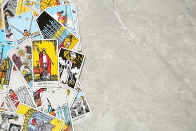 Photo of Tarot cards on light grey marble table, top view. Space for text