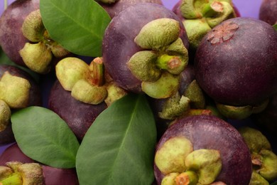 Photo of Delicious fresh mangosteen fruits with leaves as background, closeup
