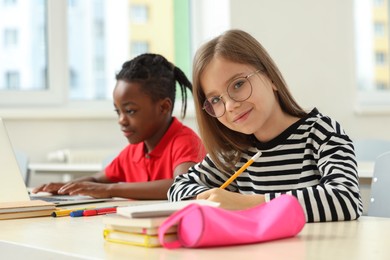Photo of Cute girl with her classmate studying in classroom at school