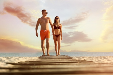 Young woman in bikini spending time with her boyfriend on beach. Lovely couple