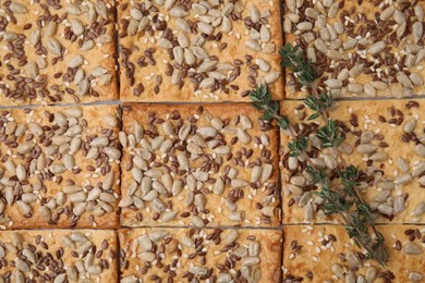 Photo of Thyme on cereal crackers with flax, sunflower and sesame seeds, top view
