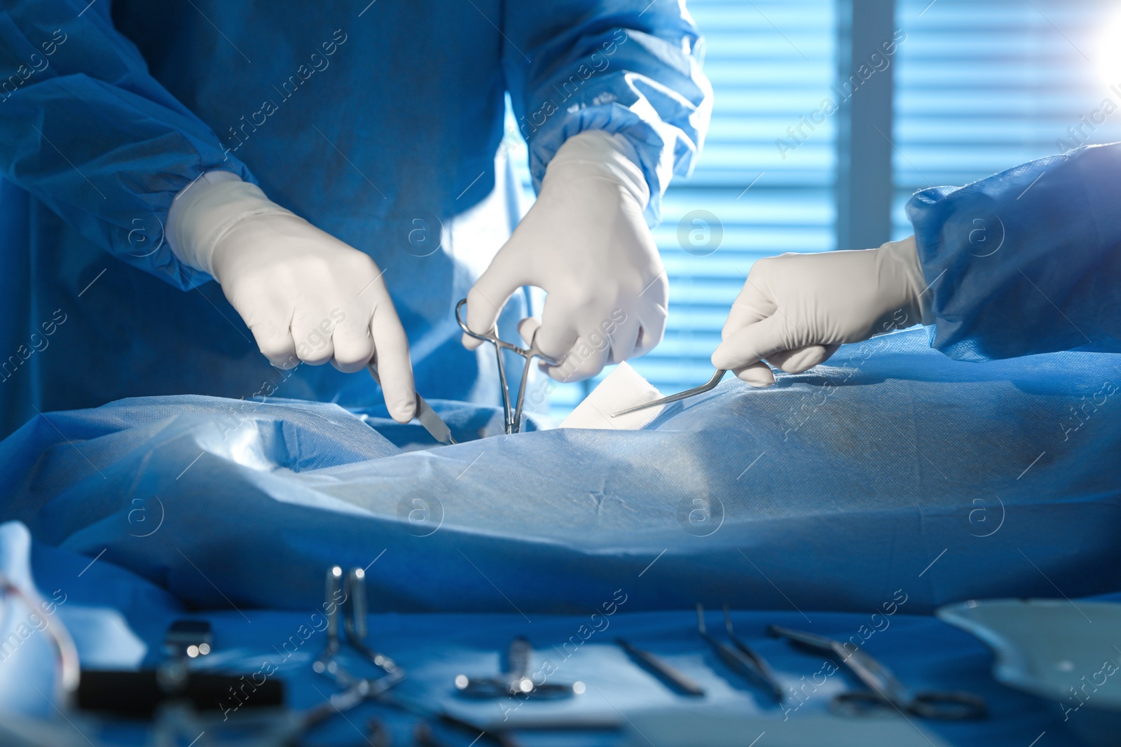 Photo of Professional surgeons with instruments performing operation in clinic, closeup