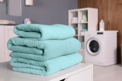 Stack of clean towels on table in laundry room. Space for text