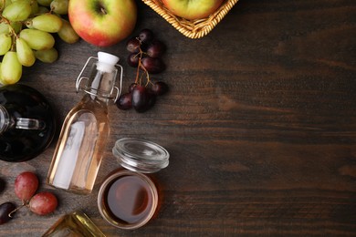 Photo of Different types of vinegar and fresh fruits on wooden table, flat lay. Space for text