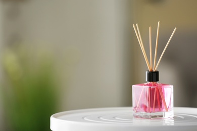 Photo of Aromatic reed air freshener on table against blurred background