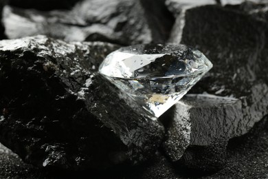 Photo of Beautiful shiny diamond on wet coal, closeup