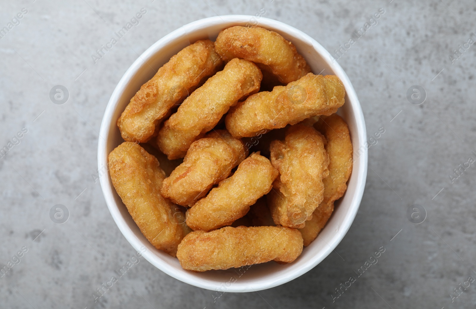 Photo of Bucket with tasty chicken nuggets on grey table, top view