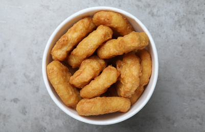 Photo of Bucket with tasty chicken nuggets on grey table, top view
