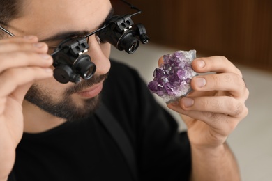 Photo of Male jeweler evaluating semi precious gemstone in workshop, closeup