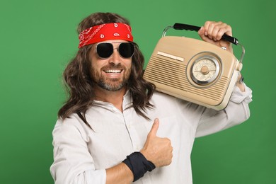 Photo of Stylish hippie man with radio showing thumbs up on green background