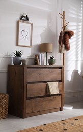 Stylish room interior with wooden chest of drawers near white wall