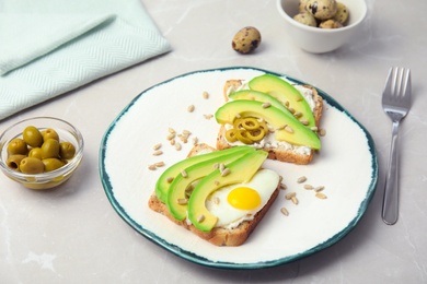 Photo of Crisp toasts with avocado and quail egg on plate