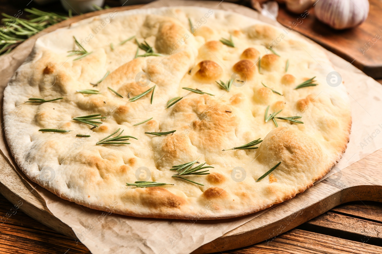 Photo of Focaccia bread with rosemary on wooden table, closeup