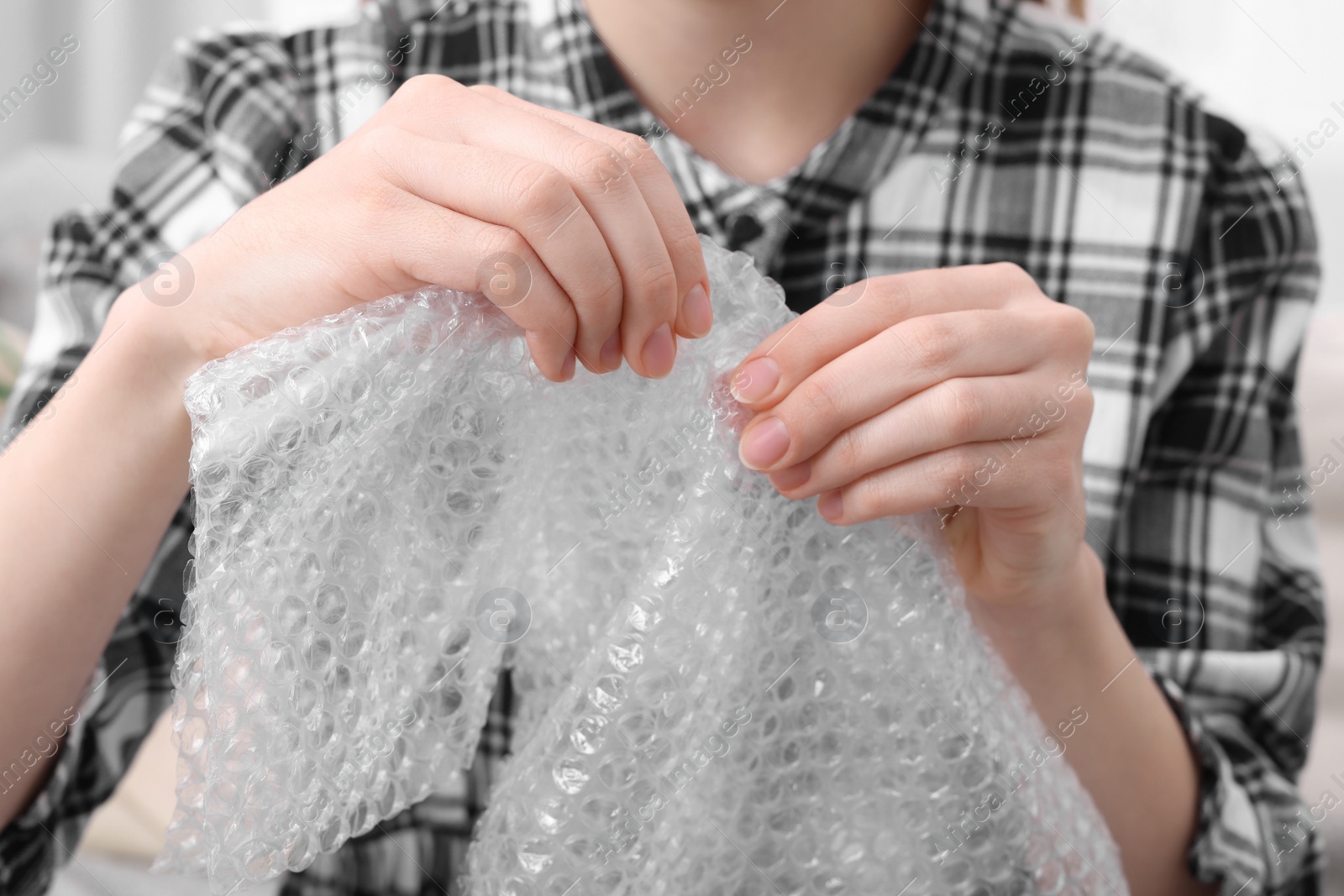 Photo of Woman popping bubble wrap, closeup. Stress relief