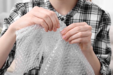 Woman popping bubble wrap, closeup. Stress relief