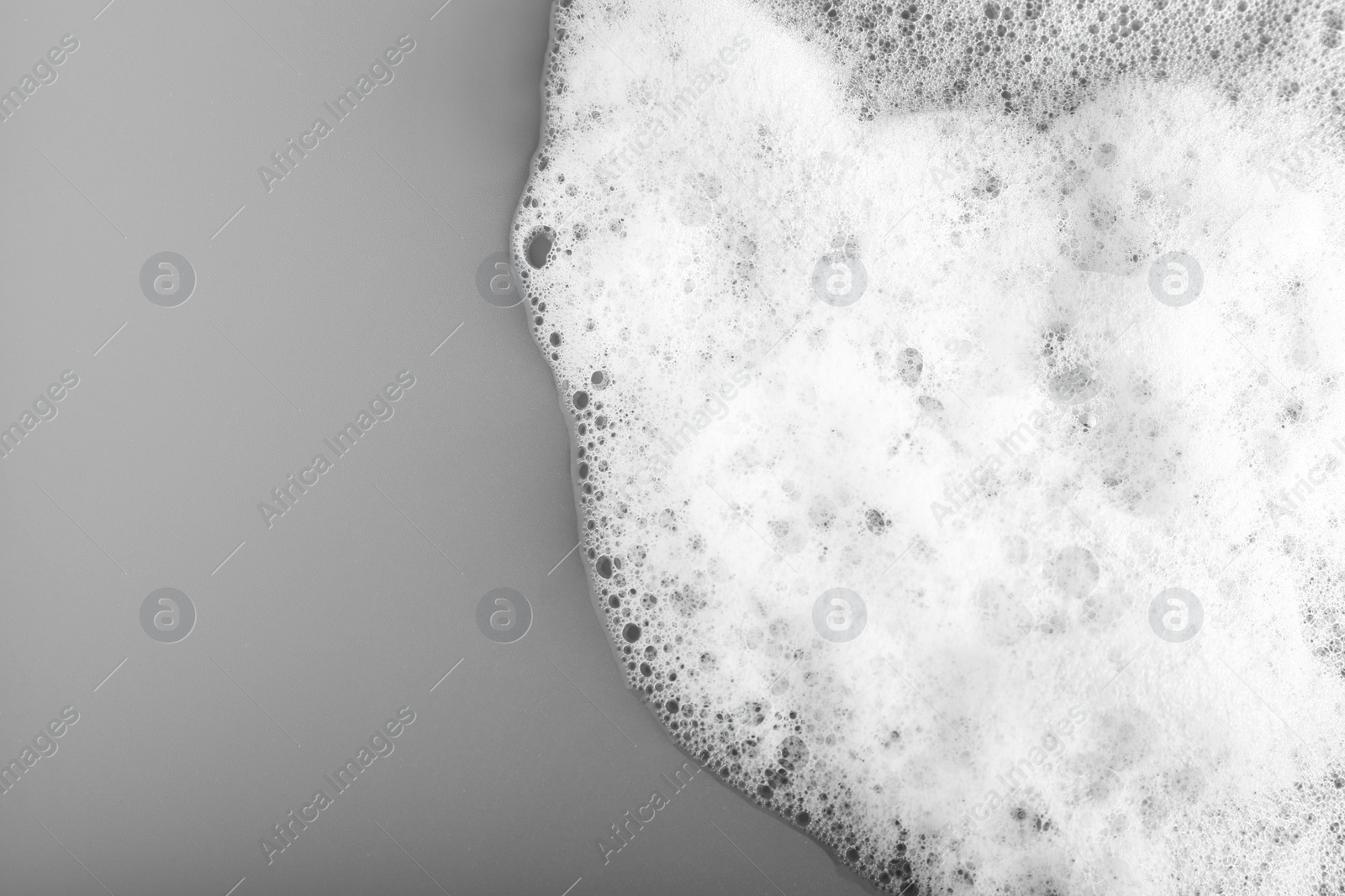 Photo of White foam with bubbles on grey background, top view. Space for text