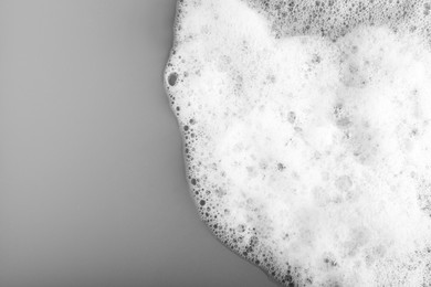 Photo of White foam with bubbles on grey background, top view. Space for text