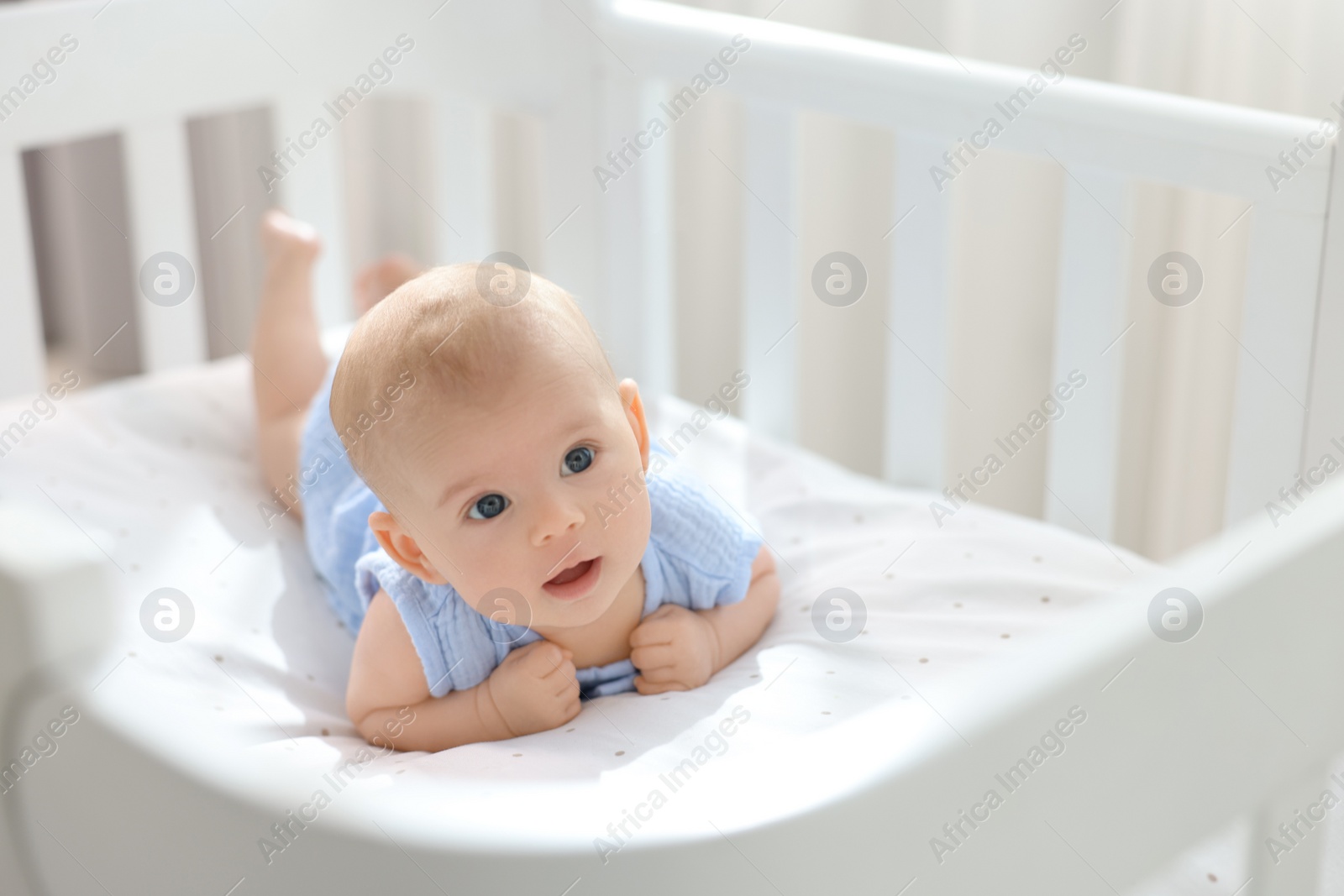 Photo of Cute little baby lying in crib at home, space for text