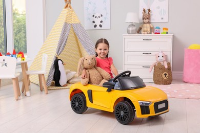 Adorable child with toy driving car in room at home
