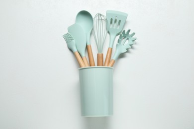 Photo of Set of kitchen utensils in holder on white table, top view