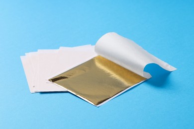 Photo of Edible gold leaf sheets on light blue background