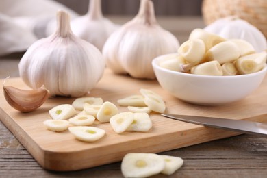 Photo of Aromatic cut garlic, cloves and bulbs on wooden table, closeup