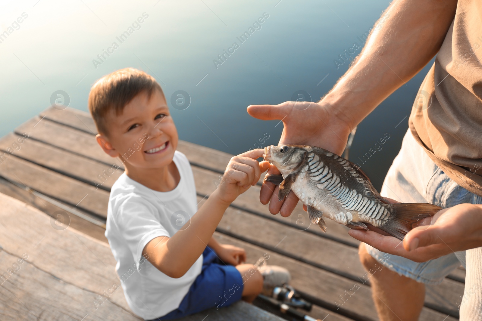 Photo of Dad and son holding caught fish at lake