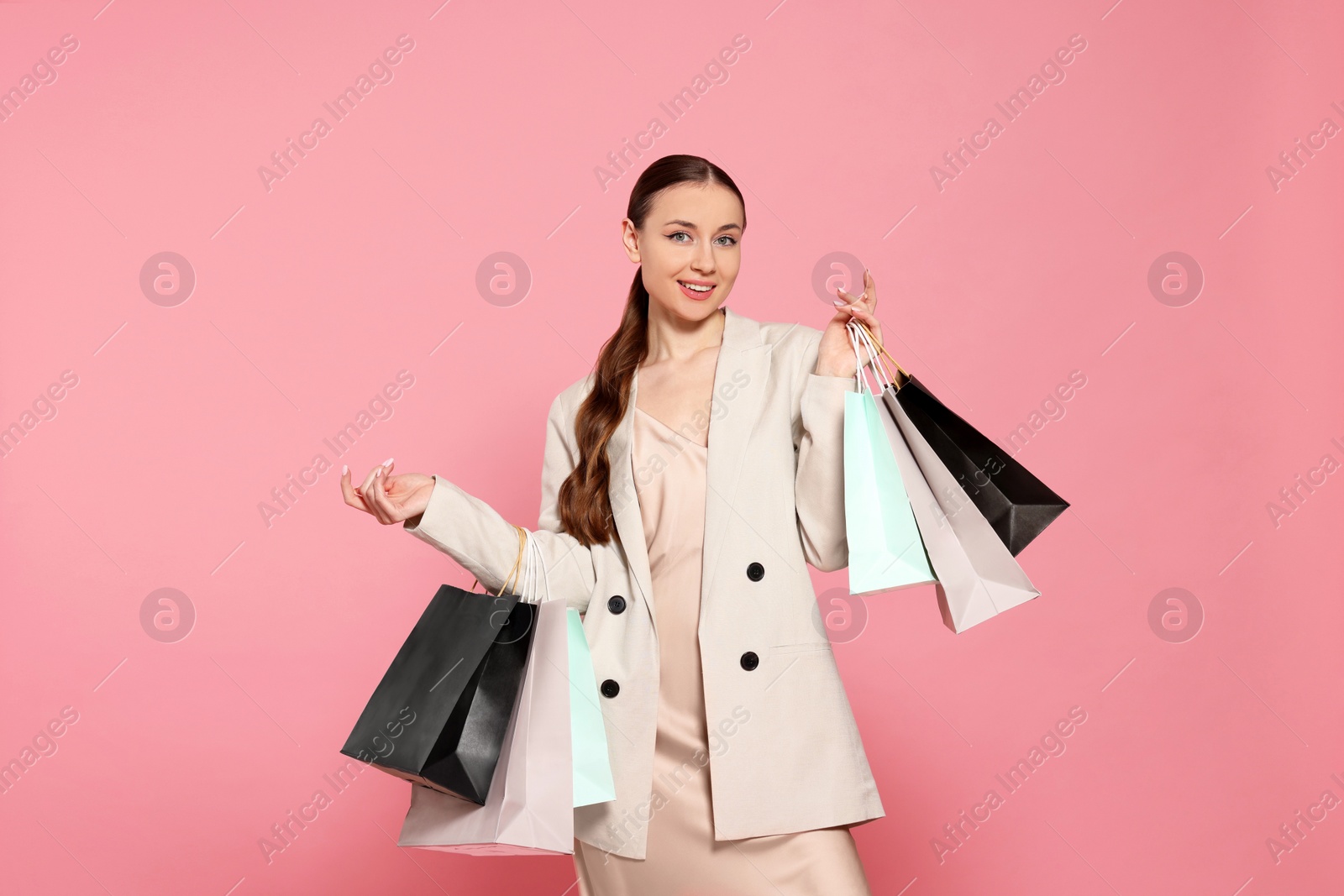 Photo of Stylish young woman with shopping bags on pink background