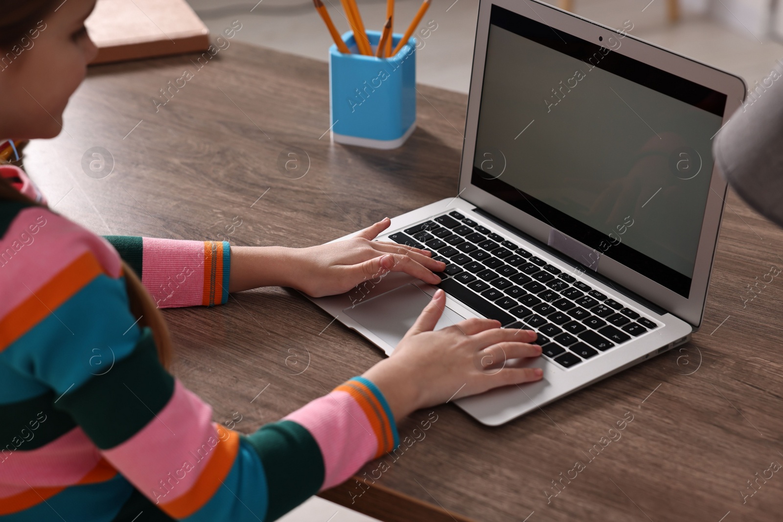 Photo of E-learning. Girl using laptop during online lesson at table indoors, closeup