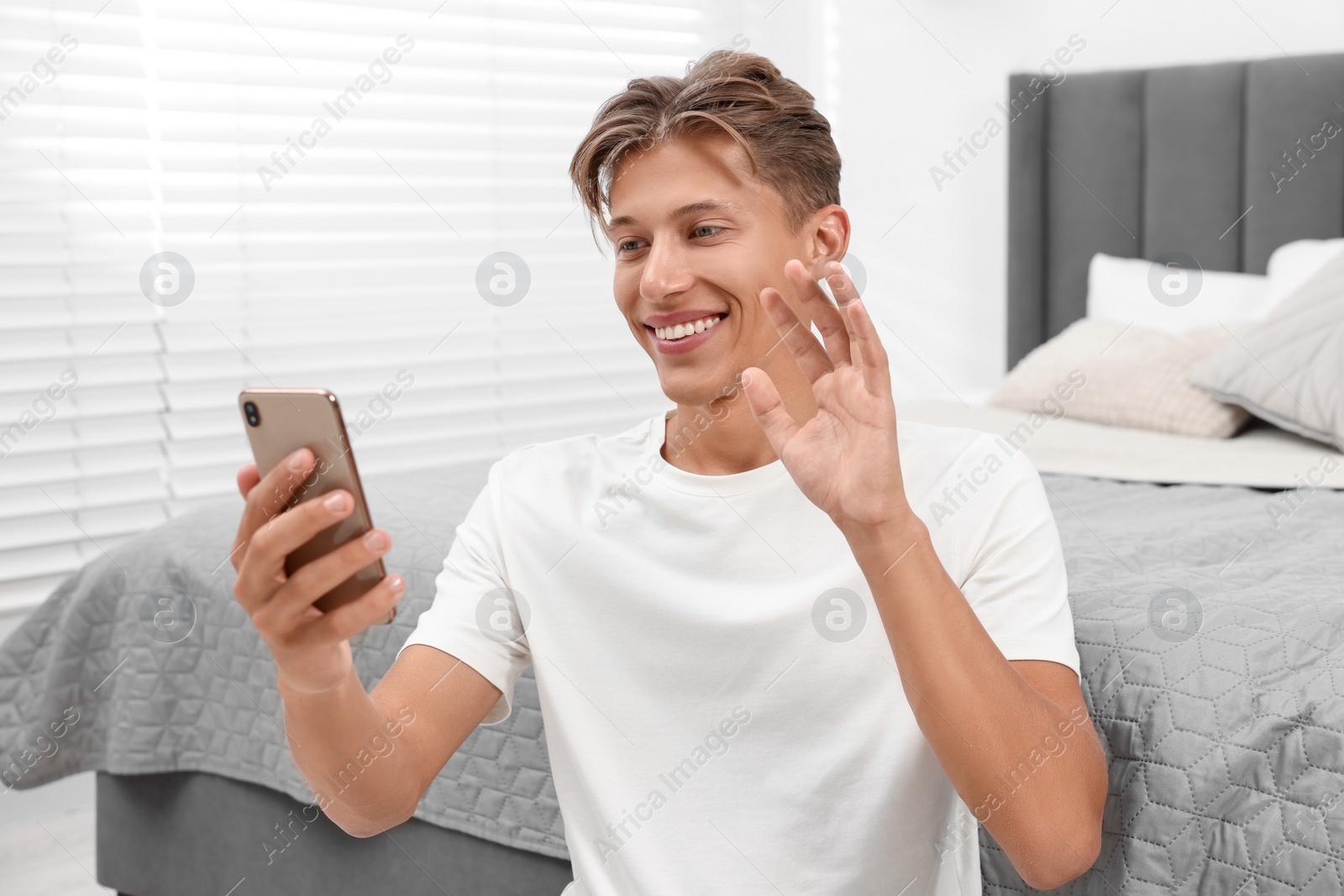 Photo of Happy young man having video chat via smartphone indoors
