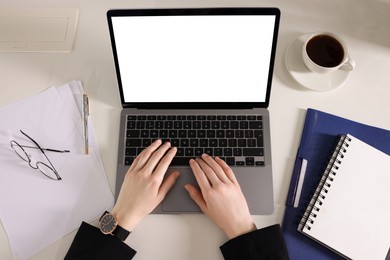 Photo of Woman working with laptop at white desk, top view