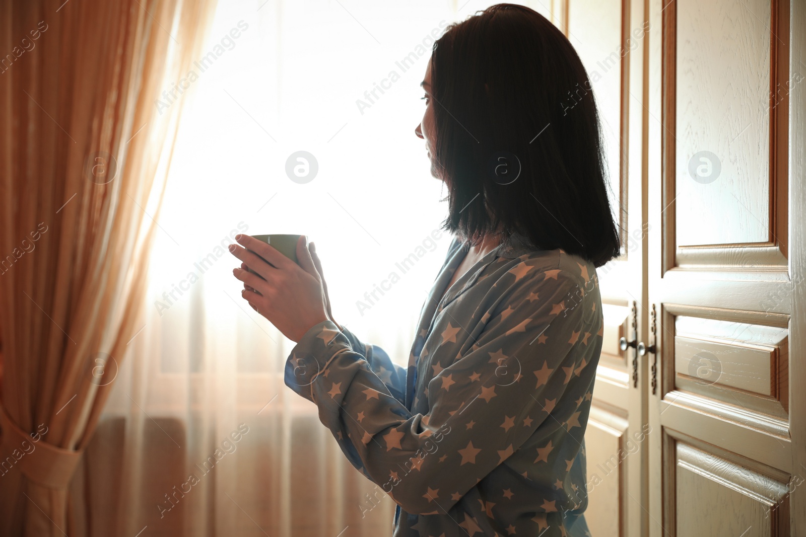 Photo of Young woman with drink near window at home. Lazy morning