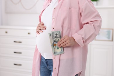 Photo of Surrogate mother. Pregnant woman with dollar banknotes indoors, closeup