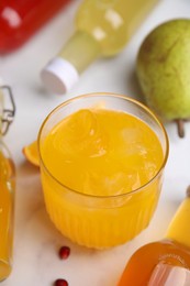 Photo of Tasty kombucha in glass and bottles on white table, closeup