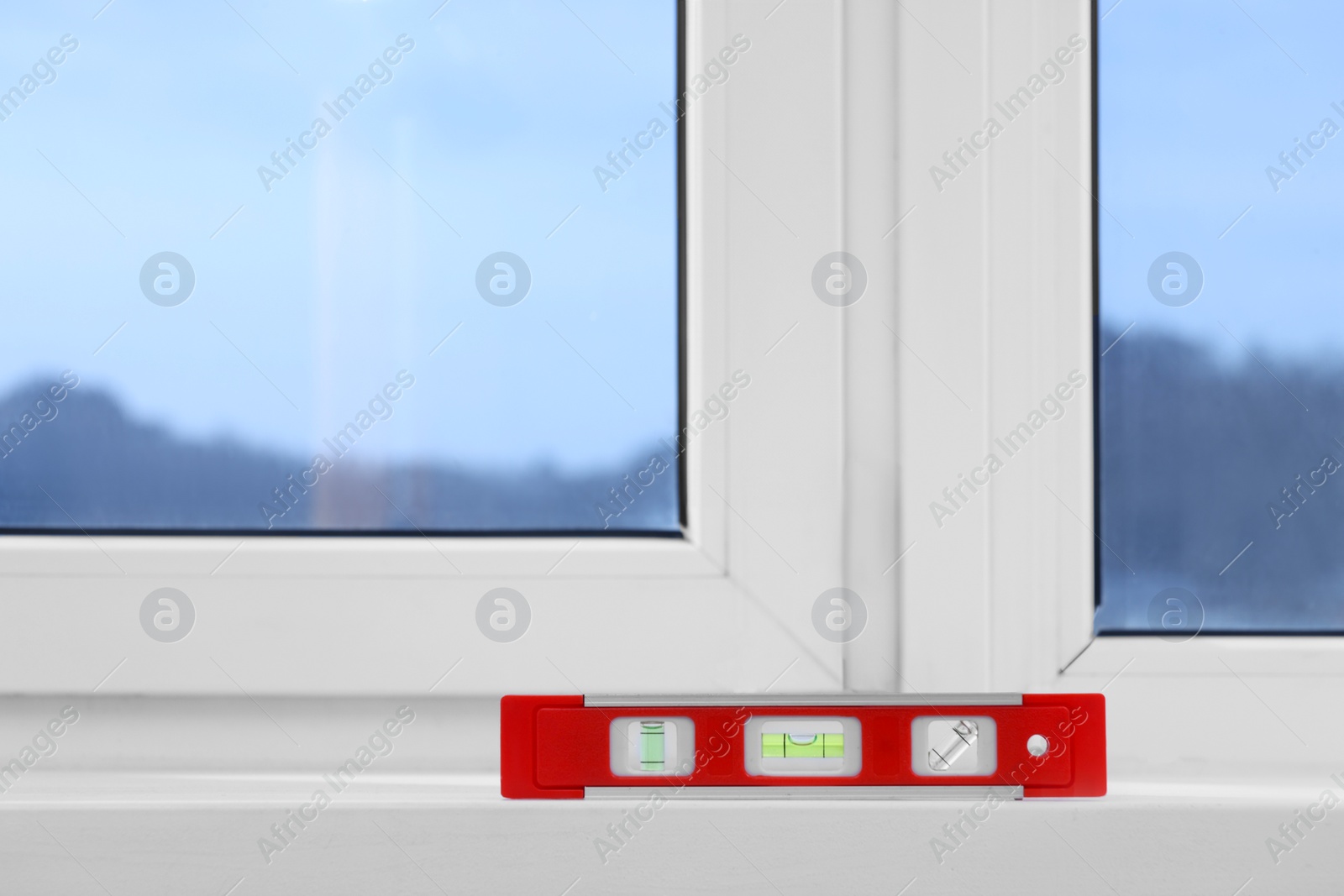 Photo of Red building level on white windowsill indoors, space for text