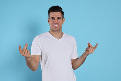Photo of Handsome man snapping fingers on light blue background