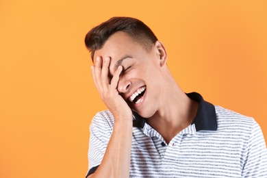 Photo of Portrait of handsome young man laughing on color background